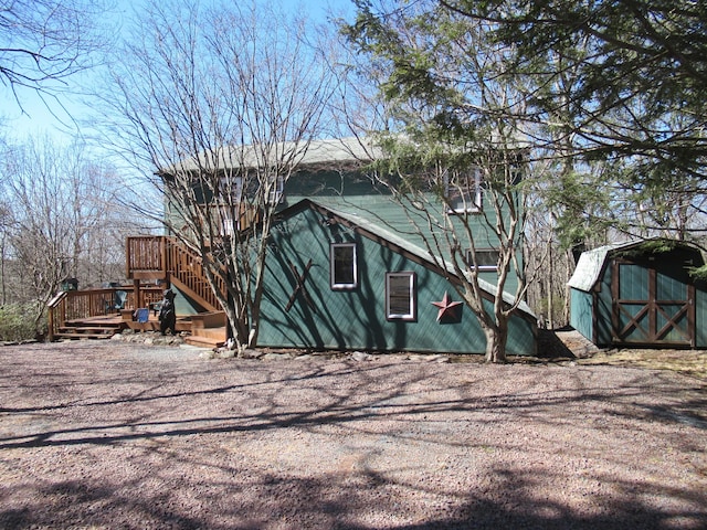 view of home's exterior with a storage unit, a deck, an outdoor structure, and stairway