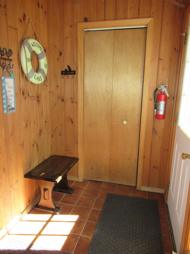 doorway featuring tile patterned floors and wooden walls