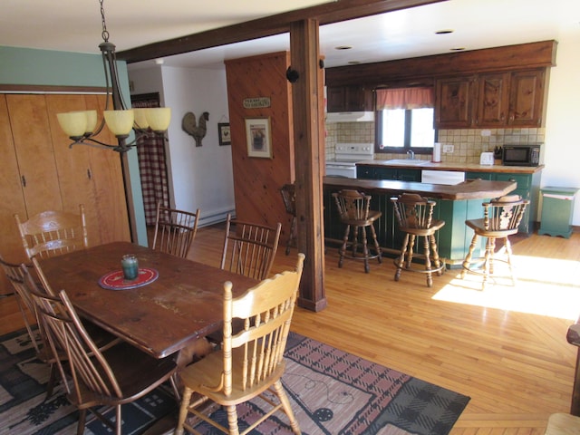 dining space with wooden walls, light wood finished floors, and a baseboard radiator