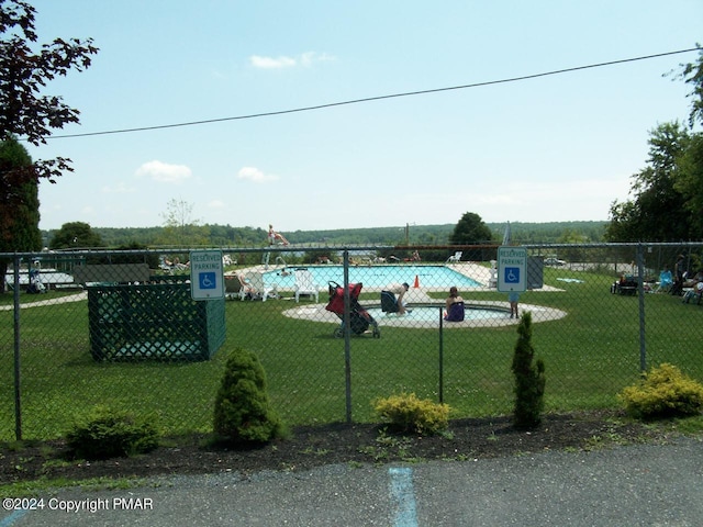 view of swimming pool with fence and a yard