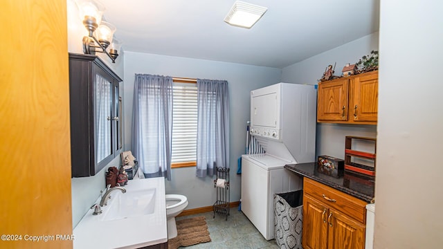 bathroom with stacked washer and clothes dryer, baseboards, vanity, and toilet