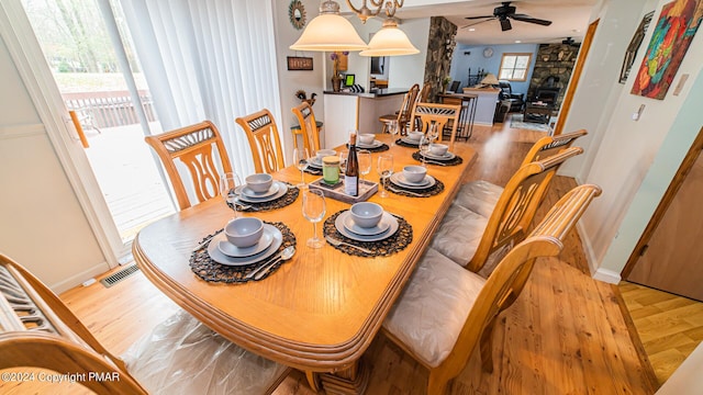 dining room featuring light wood-style floors, baseboards, visible vents, and a ceiling fan