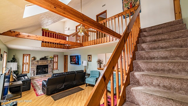 living room with hardwood / wood-style flooring, a fireplace, ceiling fan, and a high ceiling