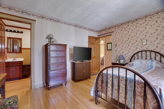 927 Hickory Valley Rd, Stroudsburg, PA 18360 - bedroom featuring light wood-style floors, wallpapered walls, a textured ceiling, a sink, and ensuite bathroom