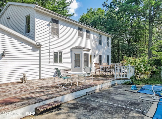 rear view of property featuring outdoor dining area and a wooden deck