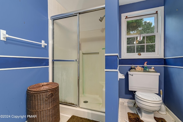 full bathroom featuring a shower with door, toilet, and tile patterned floors