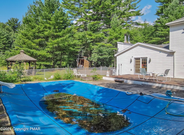 view of pool featuring a deck, a gazebo, a water slide, and fence