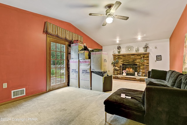 living area featuring lofted ceiling, carpet flooring, visible vents, a ceiling fan, and a brick fireplace