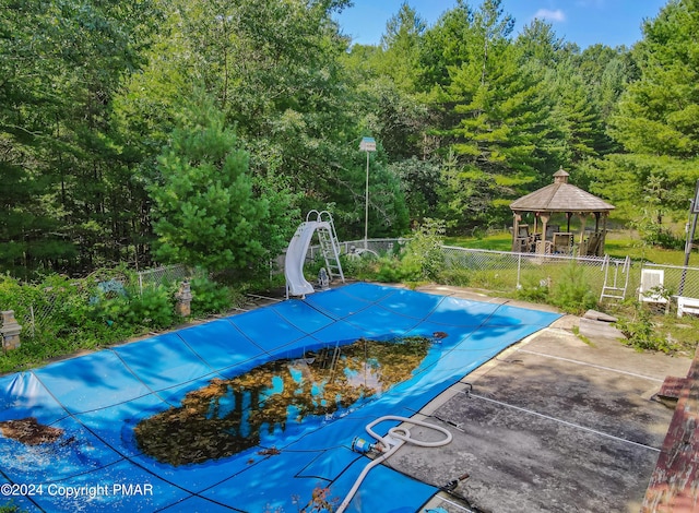 view of swimming pool with a fenced in pool, a water slide, fence, and a gazebo