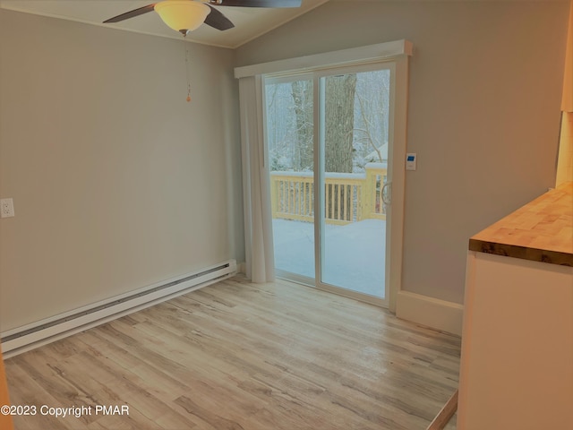 unfurnished dining area featuring baseboard heating, vaulted ceiling, ceiling fan, light wood-type flooring, and baseboards