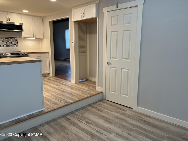 kitchen with light wood-style floors, tasteful backsplash, appliances with stainless steel finishes, and white cabinets