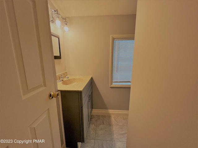 bathroom with marble finish floor, vanity, and baseboards