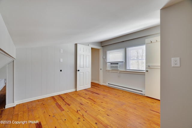 unfurnished room featuring a baseboard heating unit, cooling unit, hardwood / wood-style flooring, and baseboards