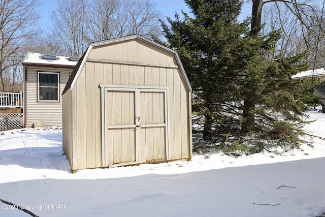 snow covered structure with an outbuilding and a storage unit