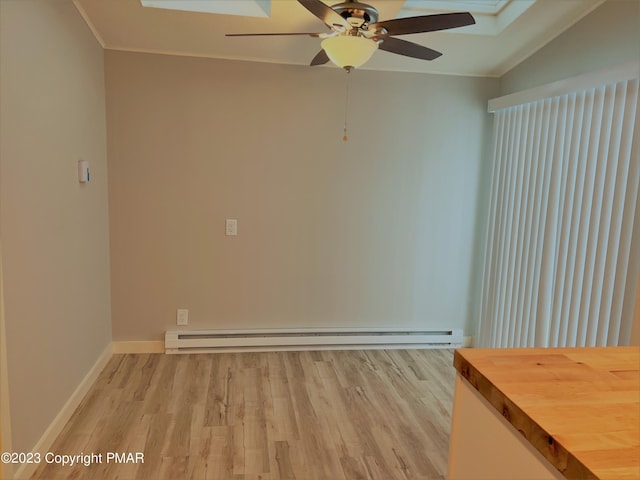 unfurnished room with a skylight, crown molding, light wood-style flooring, a baseboard heating unit, and baseboards