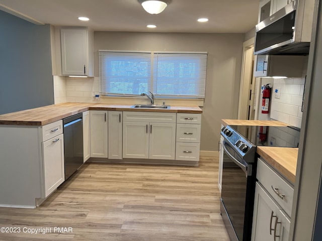 kitchen featuring wooden counters, light wood-type flooring, a sink, and stainless steel appliances