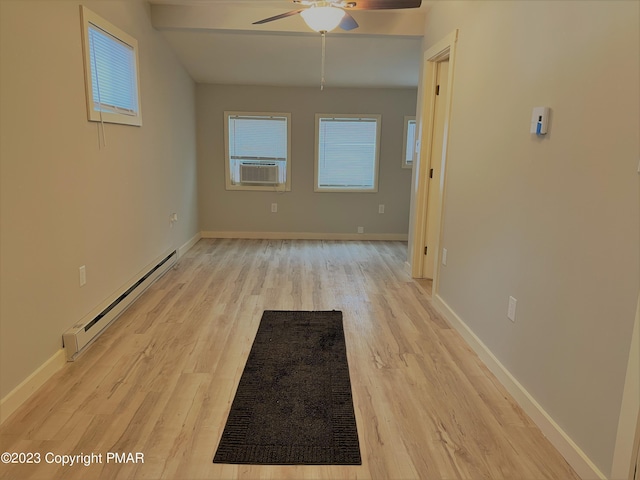 spare room featuring a baseboard heating unit, a wealth of natural light, cooling unit, and light wood-style flooring