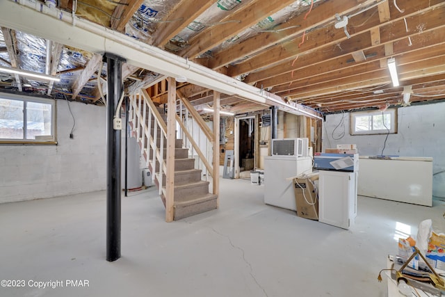 basement with water heater, stairway, washing machine and clothes dryer, and refrigerator