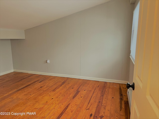 spare room featuring wood-type flooring and baseboards