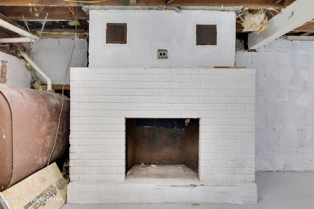 room details featuring concrete flooring, a brick fireplace, visible vents, and heating fuel