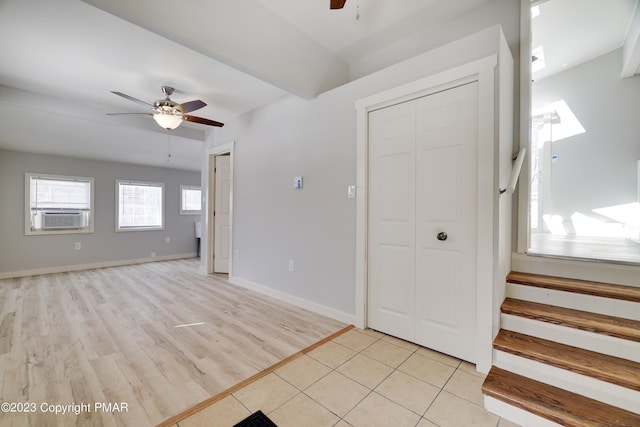 interior space featuring light tile patterned floors, ceiling fan, cooling unit, baseboards, and stairs