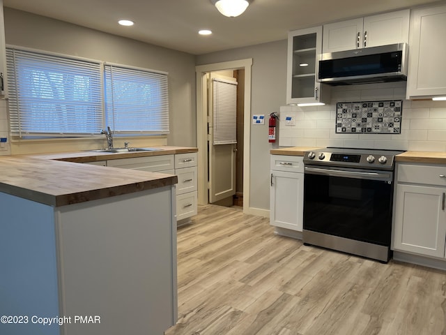 kitchen with light wood-style floors, butcher block countertops, stainless steel appliances, and a sink