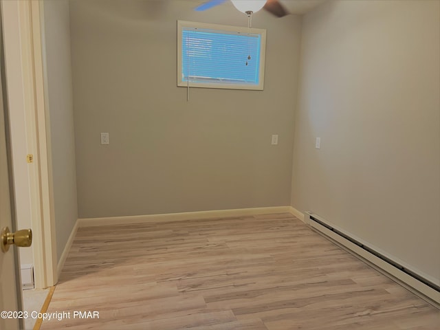 empty room featuring baseboards, ceiling fan, light wood finished floors, and baseboard heating