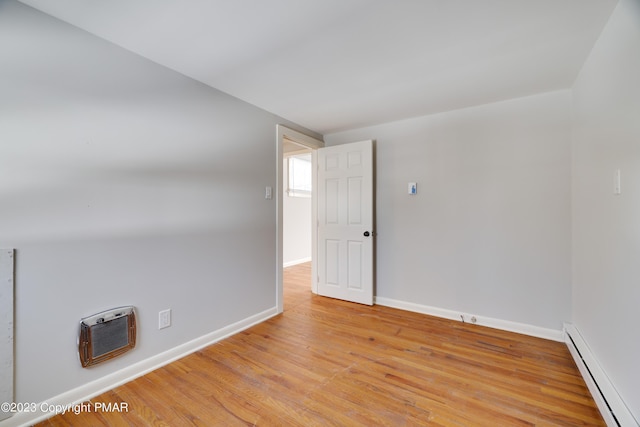 empty room featuring light wood-style floors, a baseboard radiator, heating unit, and baseboards