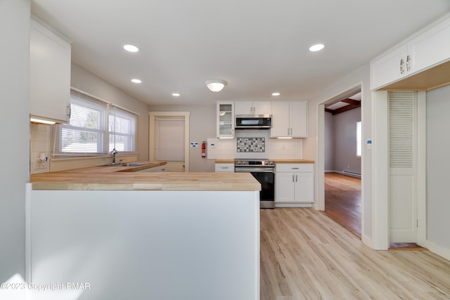 kitchen with butcher block counters, light wood-style flooring, backsplash, appliances with stainless steel finishes, and white cabinetry