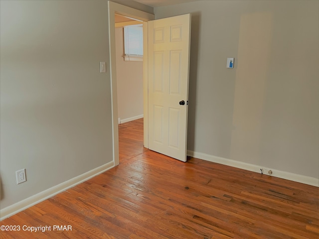 spare room featuring baseboards and wood finished floors