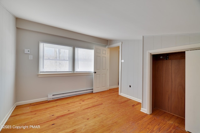 unfurnished bedroom with a baseboard radiator, a closet, baseboards, and wood finished floors