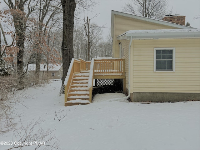 view of snow covered exterior featuring stairs, a chimney, and a deck