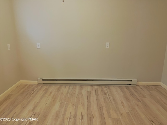 unfurnished room with a baseboard radiator, baseboards, and wood finished floors