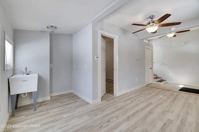 empty room featuring stairway, wood finished floors, a ceiling fan, and baseboards