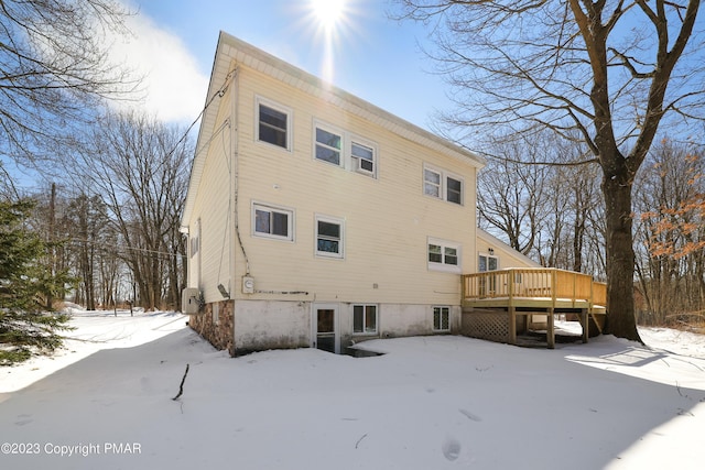 snow covered rear of property with a deck