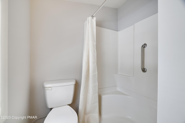 bathroom featuring a shower with curtain and toilet