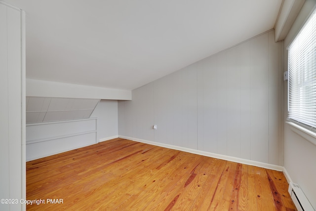 additional living space with light wood finished floors, a baseboard radiator, and baseboards