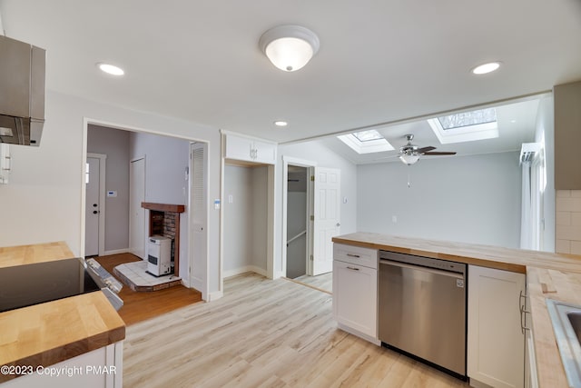 kitchen with butcher block counters, light wood-style flooring, stainless steel dishwasher, and white cabinets