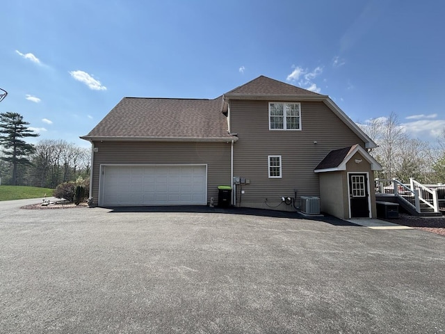389 Joanne Ct, Bartonsville, PA 18321 - back of house with central AC unit, a garage, driveway, a shingled roof, and a wooden deck