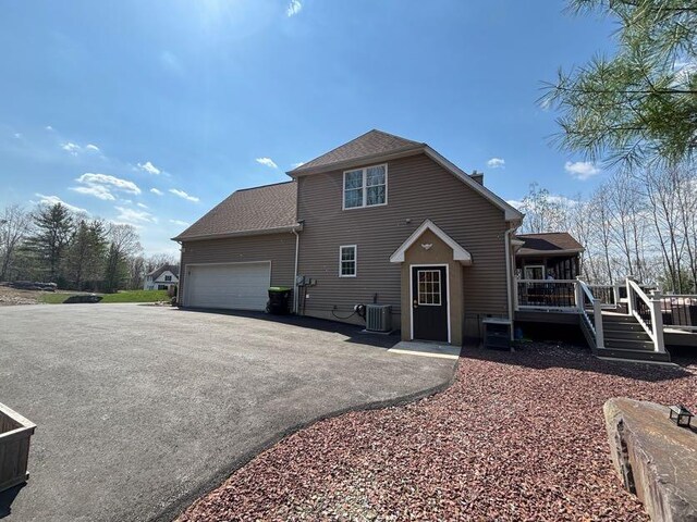 389 Joanne Ct, Bartonsville, PA 18321 - view of front of home featuring an attached garage, asphalt driveway, a wooden deck, roof with shingles, and central air condition unit