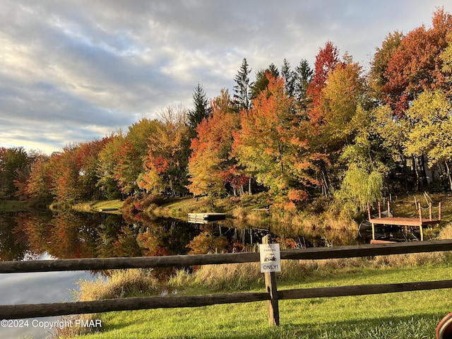 surrounding community with a water view and fence