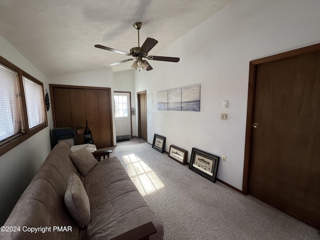 living area with baseboards, a ceiling fan, light colored carpet, vaulted ceiling, and a textured ceiling