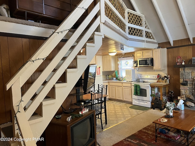 kitchen with electric range, wooden walls, stainless steel microwave, light brown cabinetry, and a sink