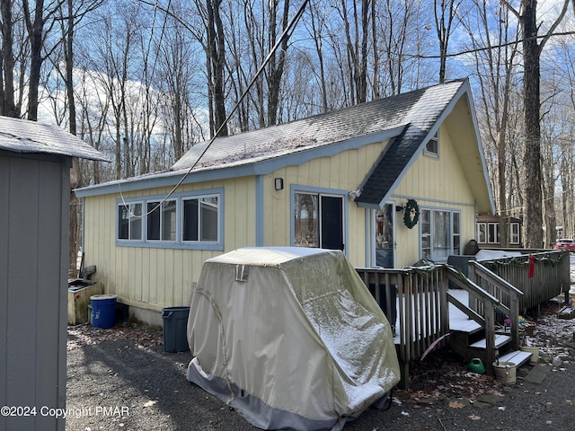 exterior space featuring roof with shingles and a wooden deck