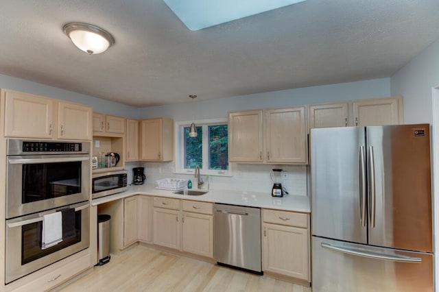 kitchen with light countertops, a sink, light brown cabinets, stainless steel appliances, and light wood-style floors
