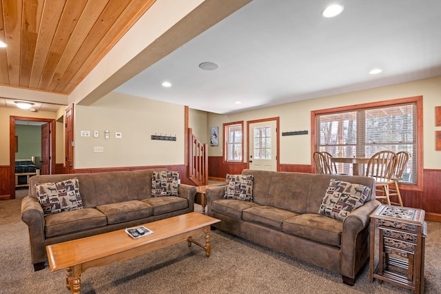 living room featuring wooden walls, a wainscoted wall, stairs, wood ceiling, and carpet flooring