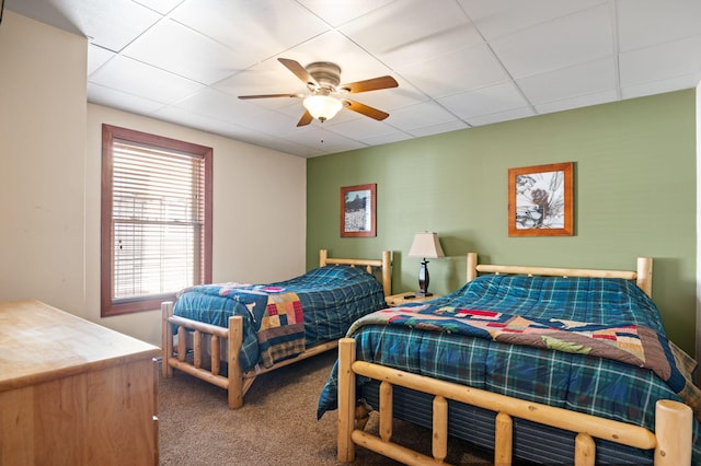 carpeted bedroom featuring a drop ceiling and a ceiling fan