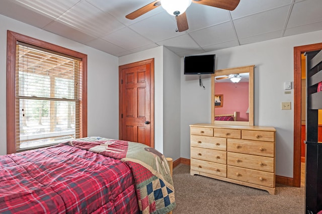 carpeted bedroom with a ceiling fan, a paneled ceiling, and baseboards