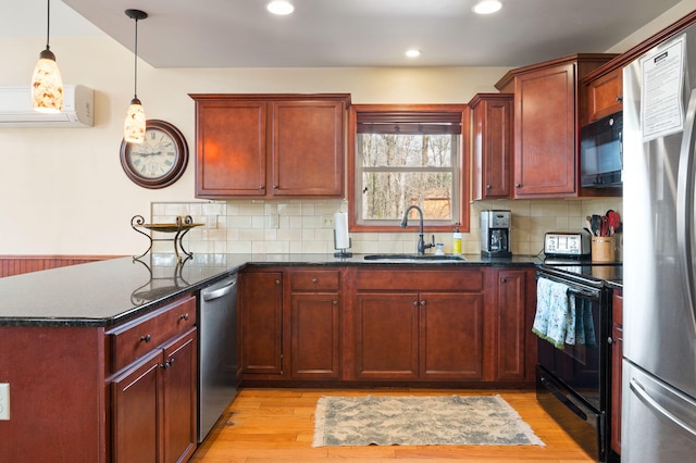 kitchen featuring an AC wall unit, a peninsula, light wood-style floors, black appliances, and a sink