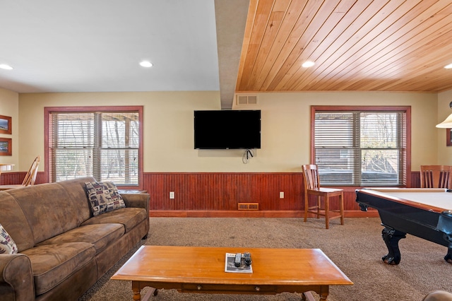 living area with visible vents, wainscoting, wood ceiling, and carpet flooring